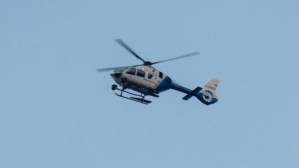 Ein Polizeihubschrauber fliegt über den Ortsrand.