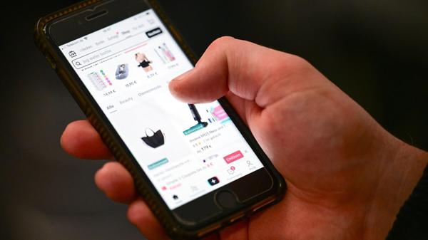 Eine Person hält ein Smartphone in der Hand und sc