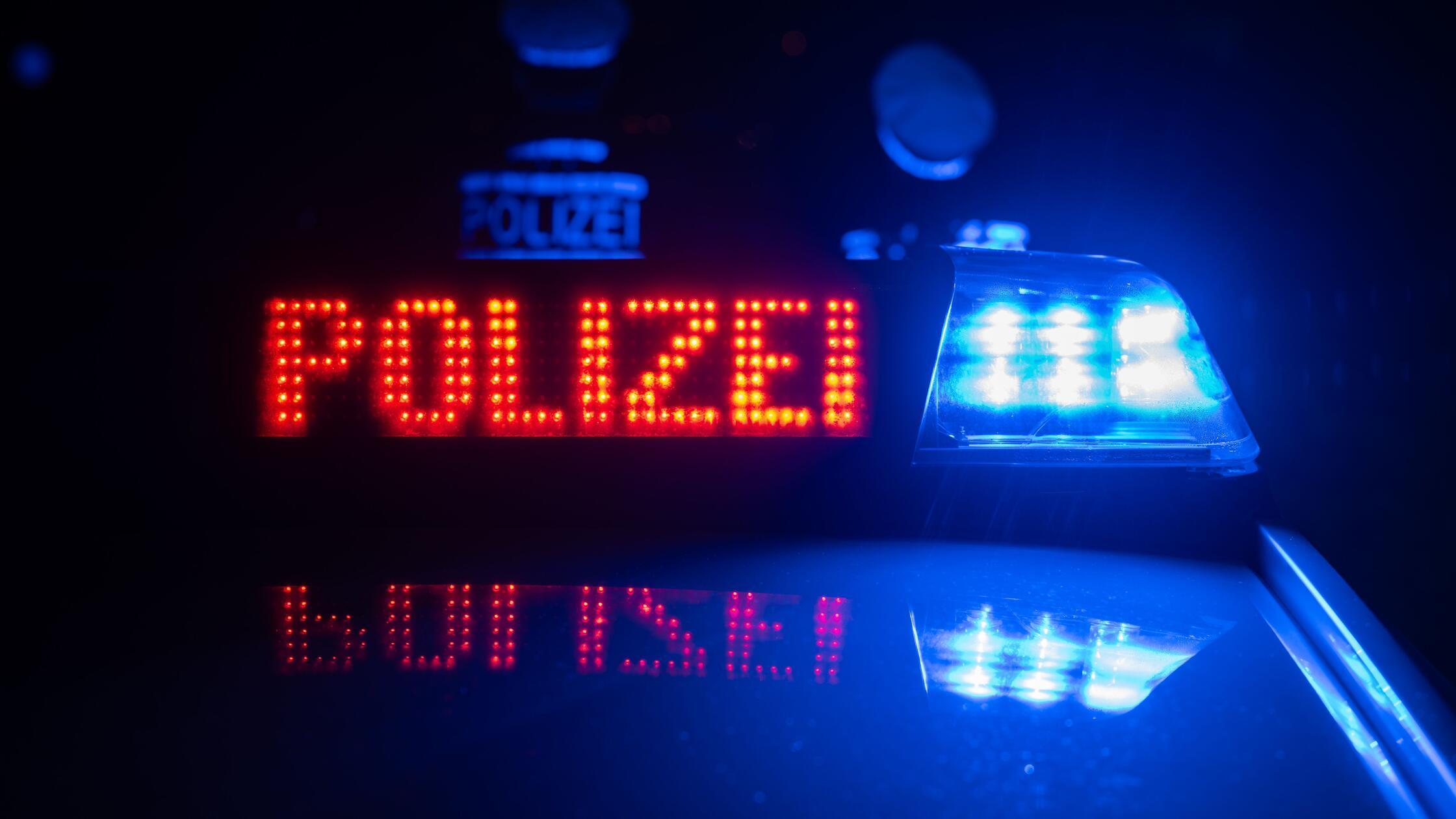 Zwei Polizisten stehen vor einem Polizeifahrzeug. 