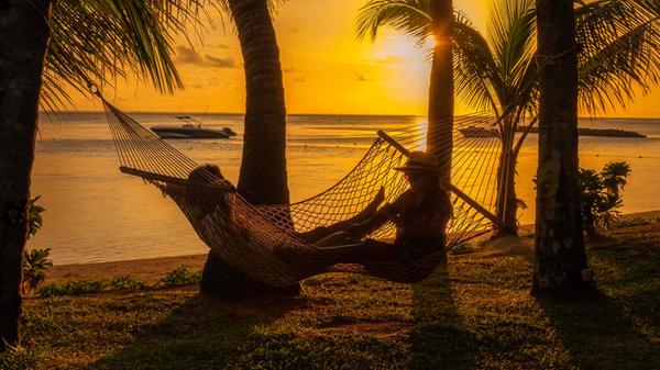 couple men and woman watching sunset on a tropical