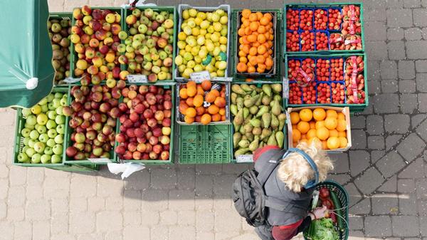 Ein Passant steht auf einem Wochenmarkt an einem M