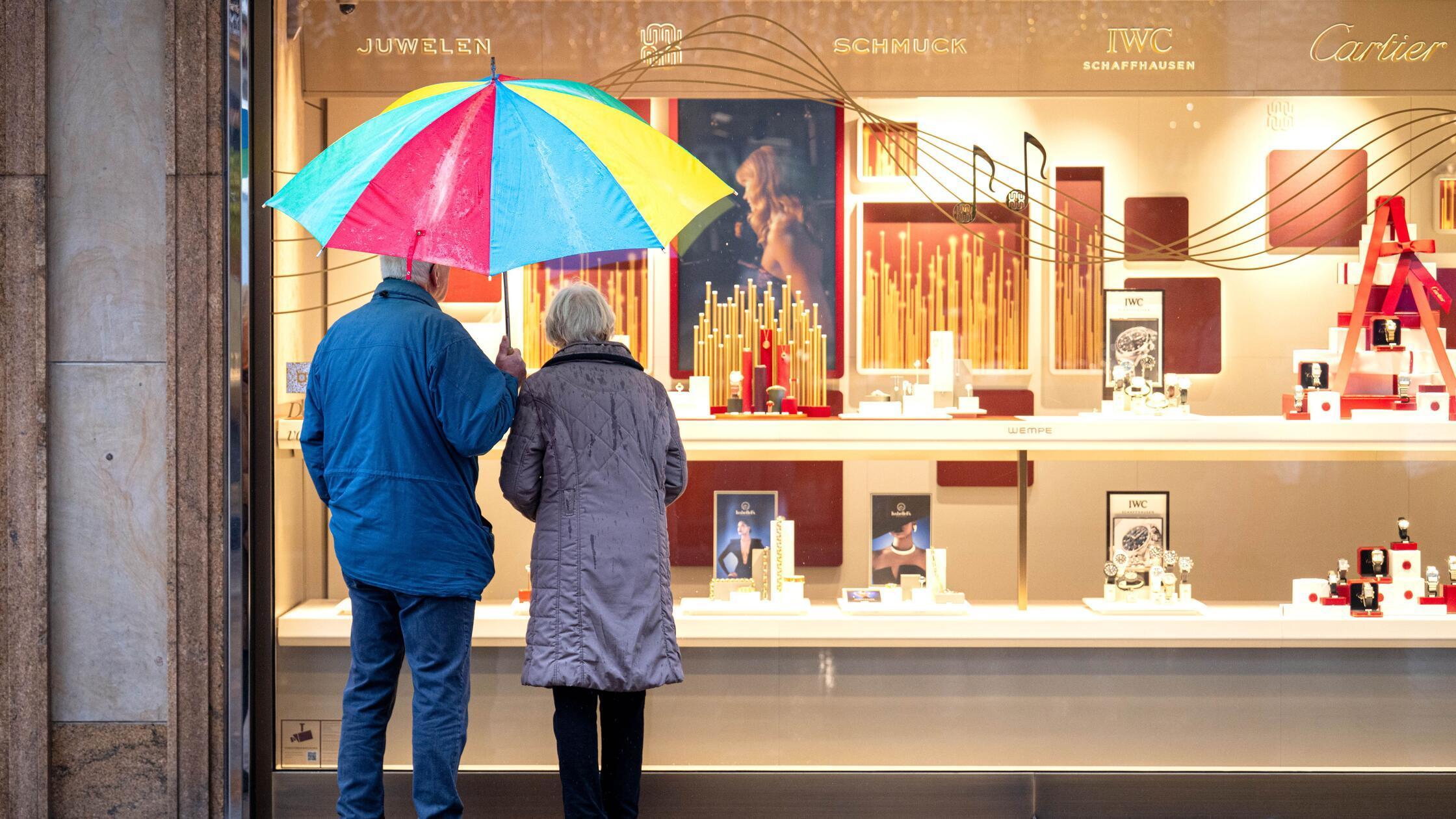 Zwei ältere Personen stehen bei Regen vor einem Sc