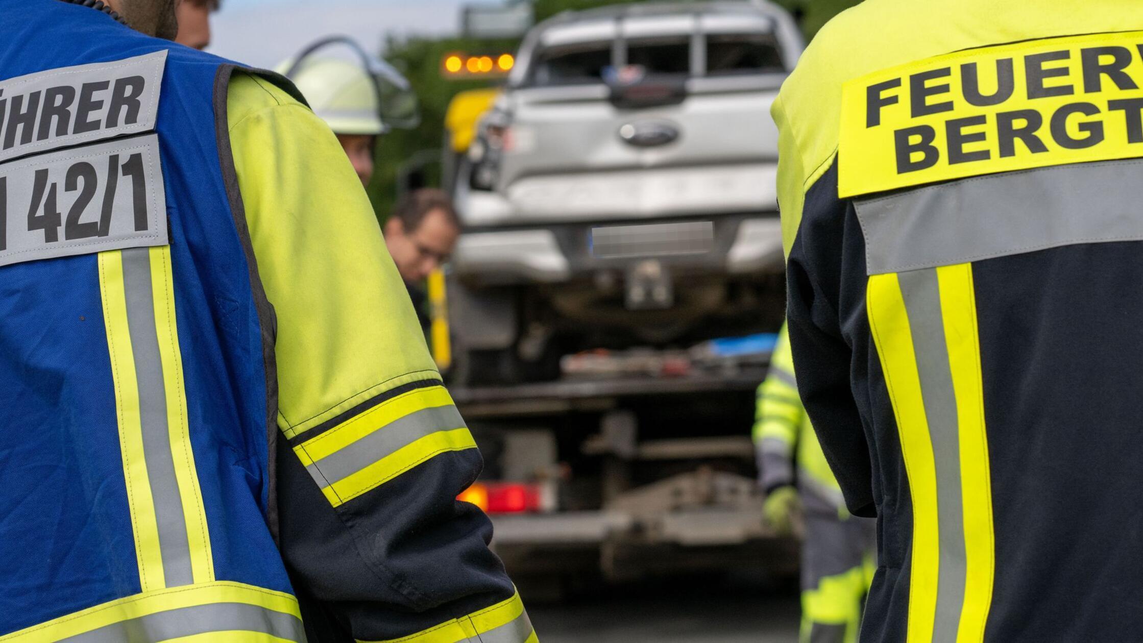 Einsatzkräfte der Feuerwehr stehen vor einem Fahrz