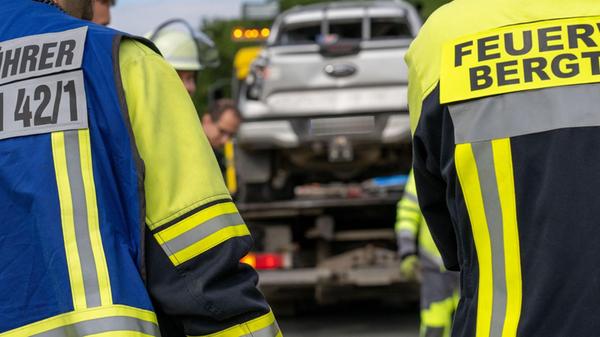 Einsatzkräfte der Feuerwehr stehen vor einem Fahrz