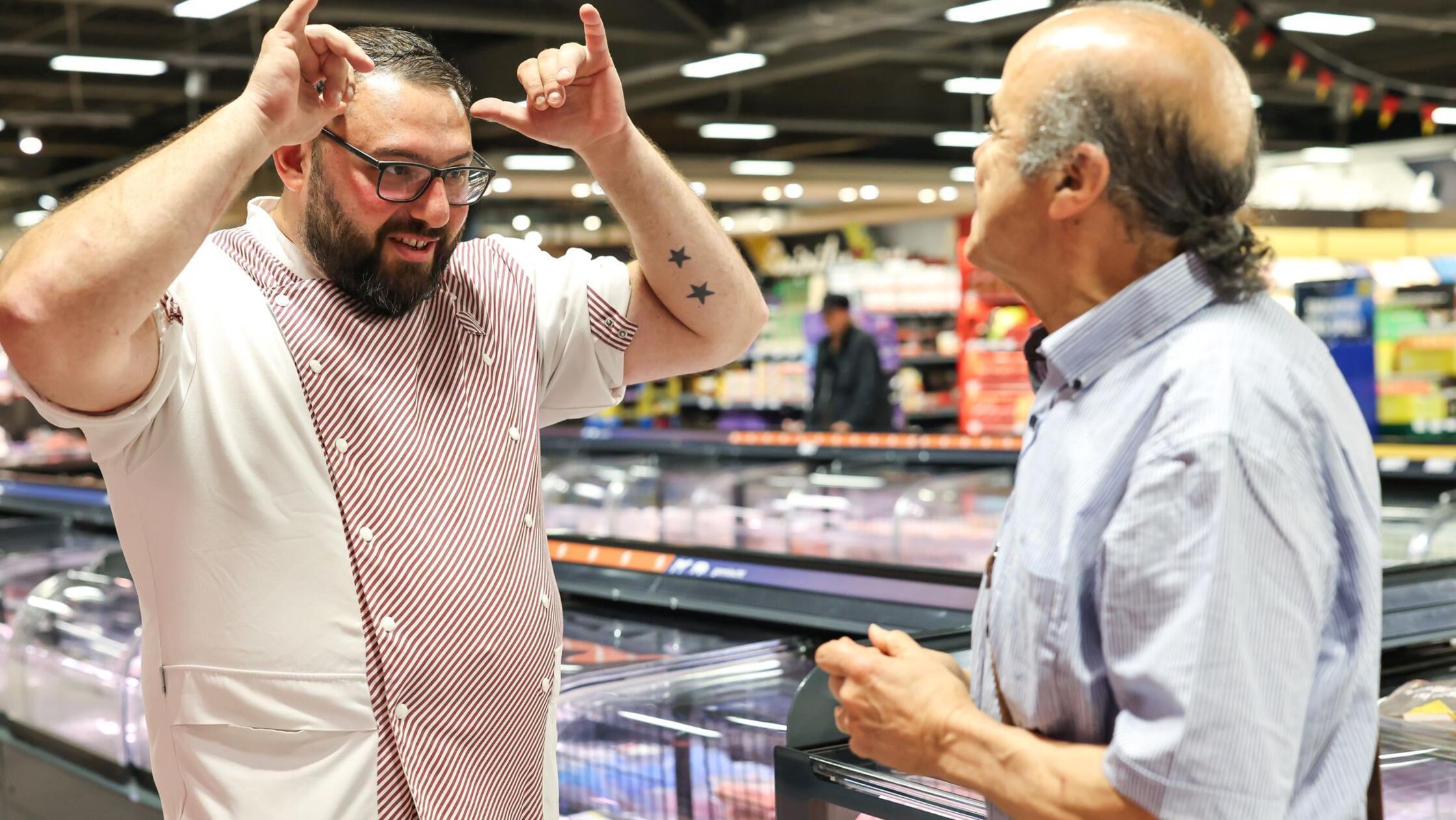 Metzger Yevgeniy Klibanov (l) lernt Gebärdensprach