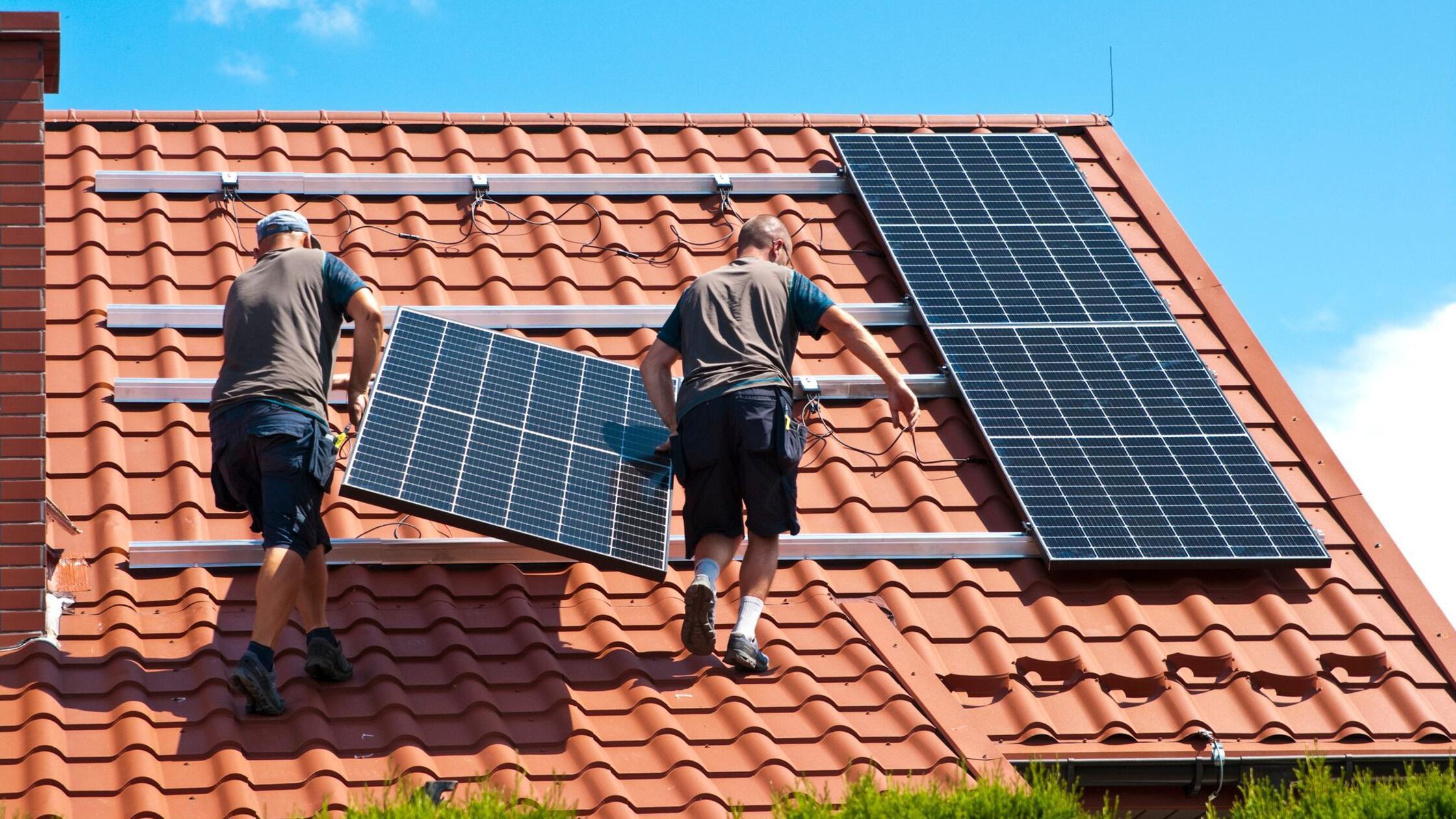 Handwerker installieren eine PV-Anlage auf dem Dac