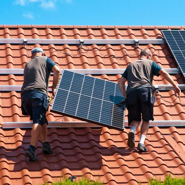 Handwerker installieren eine PV-Anlage auf dem Dac