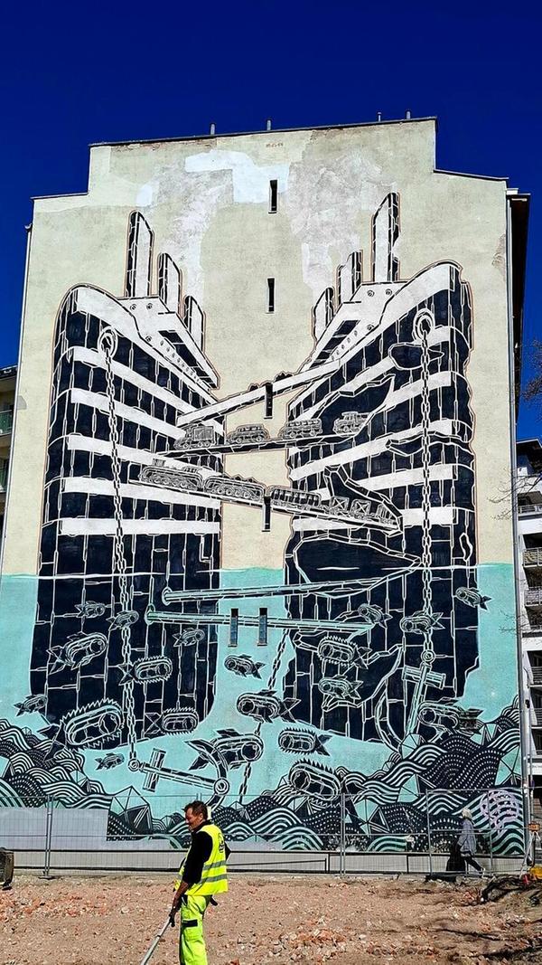 Das Bild zeigt ein großformatiges Wandgemälde (Mural) des polnischen Künstlers Mariusz Waras, bekannt als M-City, in der Hafenstadt Gdynia. Das Selbstverständnis der Stadt ist eng verknüpft mit der Emigration von Millionen von Polen in die ganze Welt. Weil die einzige Hafenstadt Danzig eine freie Handelsstadt war, wollte Polen einen eigenen Hafen bauen. So entstand aus dem Fischerdorf Gdynia vor 100 Jahren die Hafenstadt Gdynia mit heute 250.000 Einwohnern.