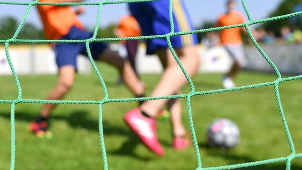 Kinder spielen auf einem Kleinfeld Fußball. Der Ba