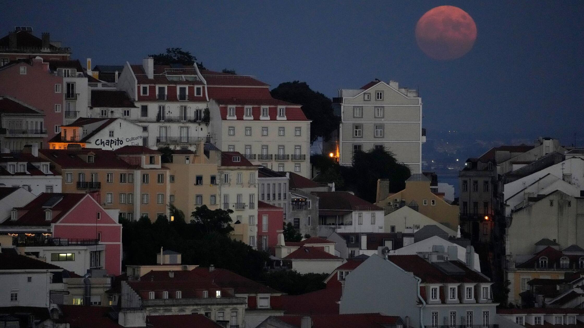 Der Vollmond geht in Lissabon hinter dem Stadtteil