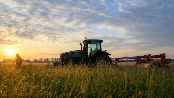 Ein Traktor steht vor der aufgehenden Sonne auf ei