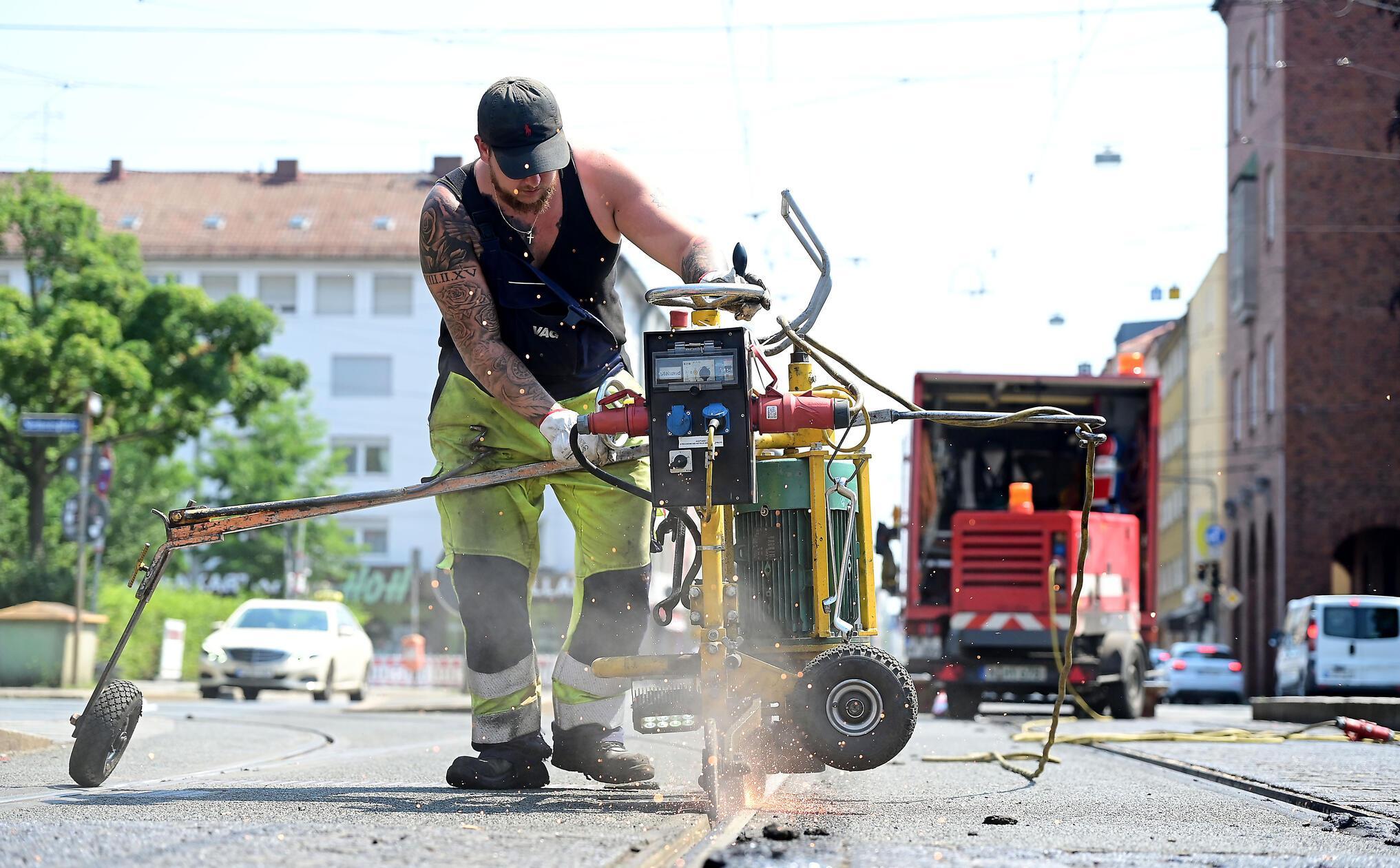 Mitarbeiter der VAG befreien in der Südstadt die Schienen von dem Bitumen. Hier in der Landgrabenstraße.