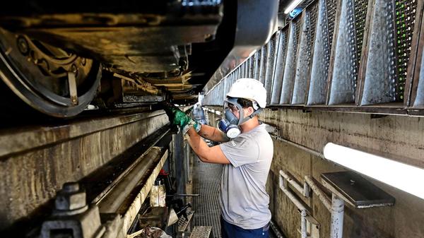 In der Werkstatt Straßenbahnbetriebshof Heinrich-Alfes-Straße beseitigen Mitarbeiter die Reste von Bitumen auf Rädern und Bremsen. Hier sind rund 70 Angestellte mit Schutzausrüstung unter den Straßenbahnen zugange.