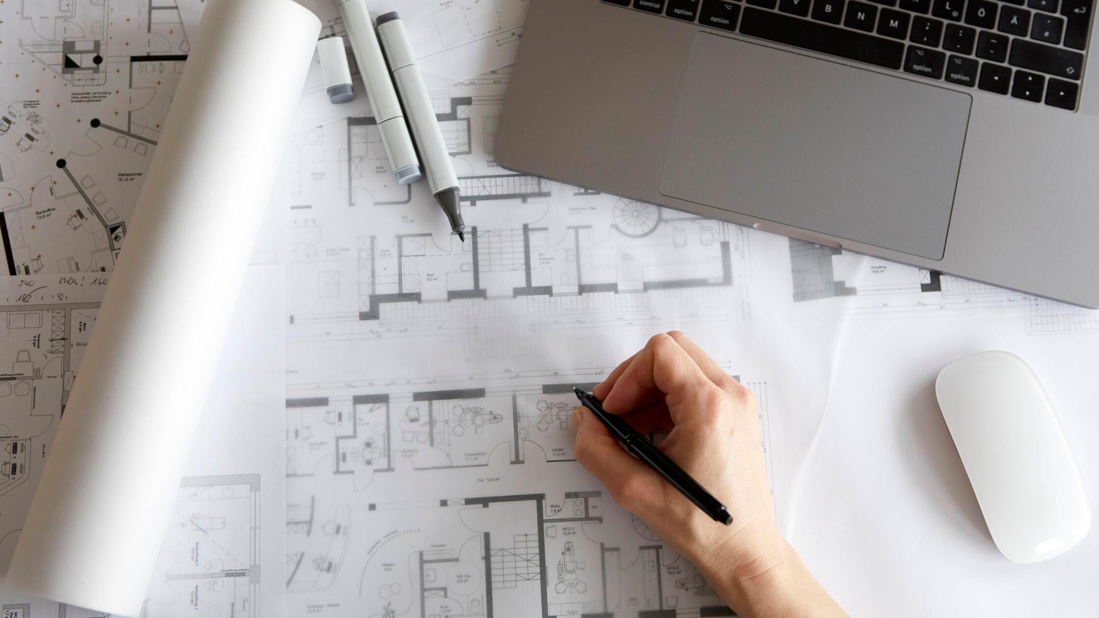 Architect working on blueprints at office desk wit
