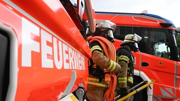 Zwei Feuerwehrleute gehen mit ihrer Ausrüstung zur
