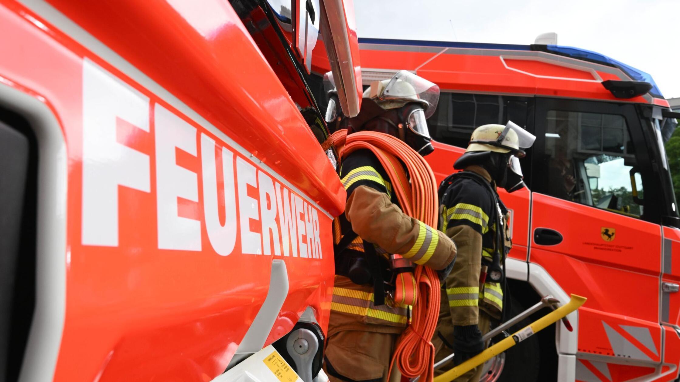 Zwei Feuerwehrleute gehen mit ihrer Ausrüstung zur