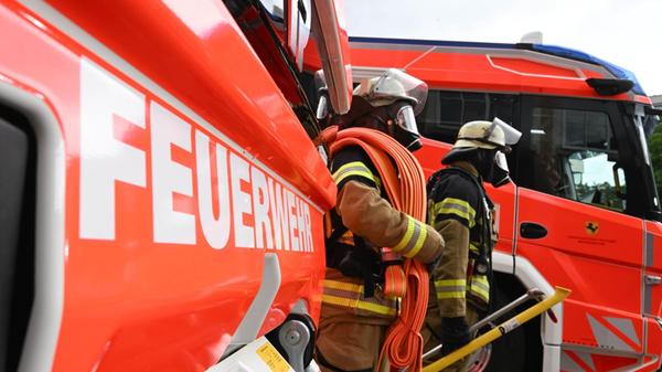 Zwei Feuerwehrleute gehen mit ihrer Ausrüstung zur