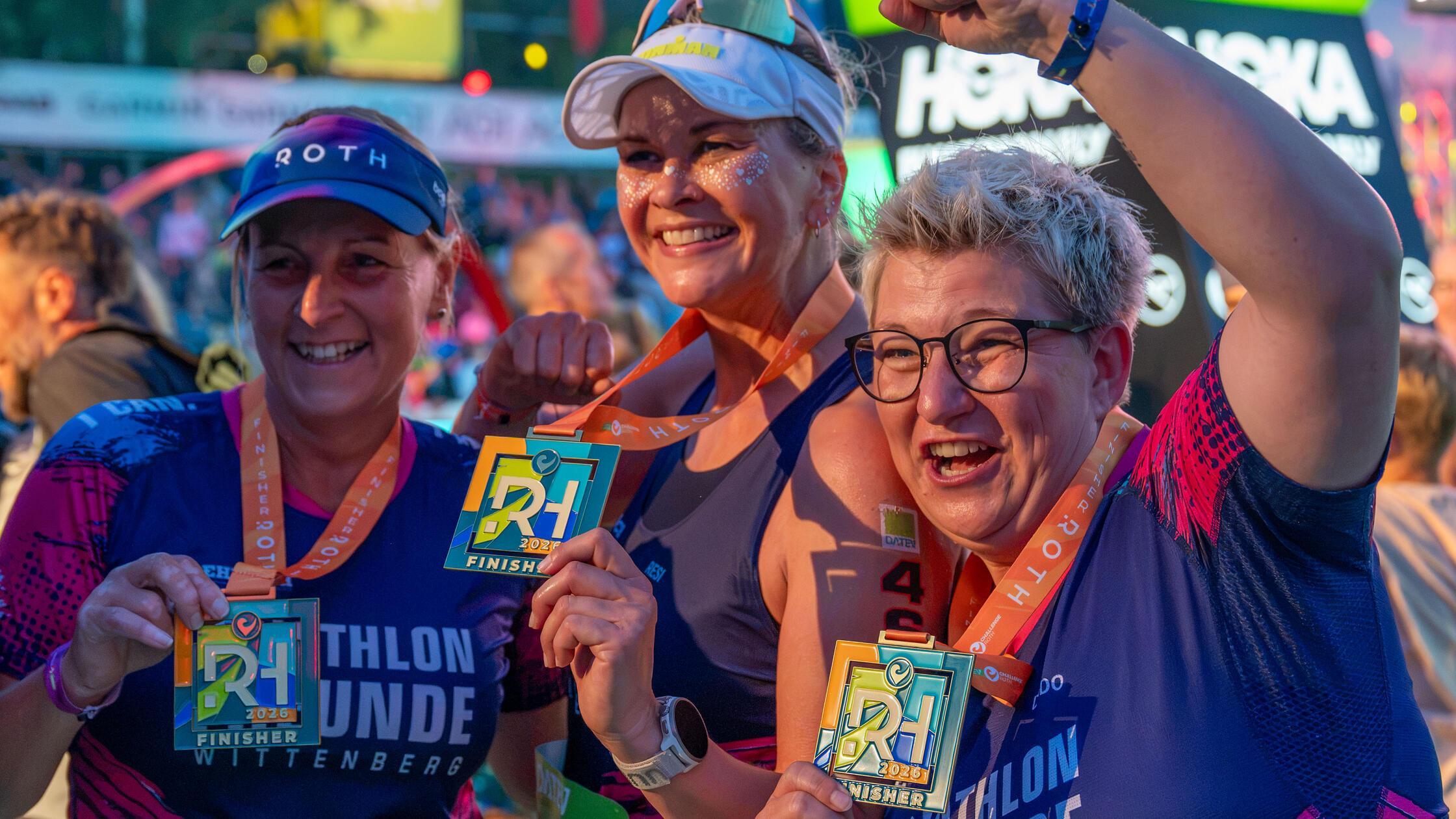 Strahlende Gesichter: Drei Finisherinnen präsentieren stolz ihre Finisher-Medaillen.