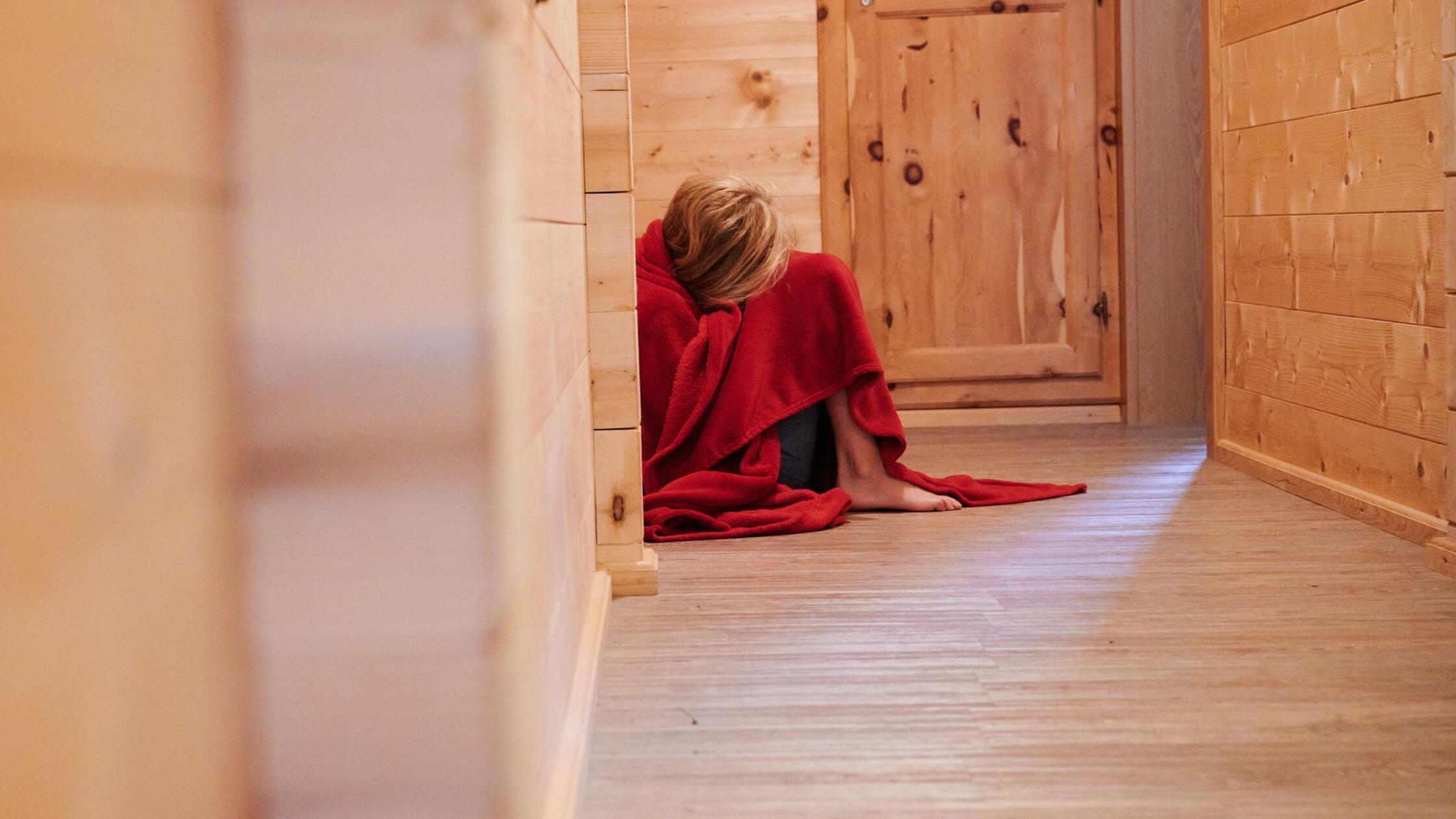 Ein Kind ist in eine Decke gewickelt und kauert au