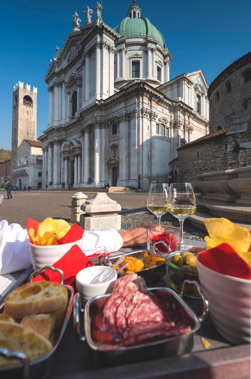 Auf der Piazza Paolo VI, genießen Einheimische und Gäste gerne Snacks und kühle Getränke mit Blick auf die Kathedrale von Brescia. 