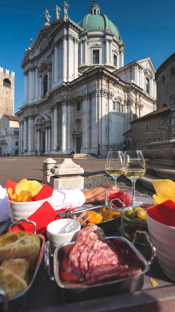 Auf der Piazza Paolo VI, genießen Einheimische und Gäste gerne Snacks und kühle Getränke mit Blick auf die Kathedrale von Brescia.