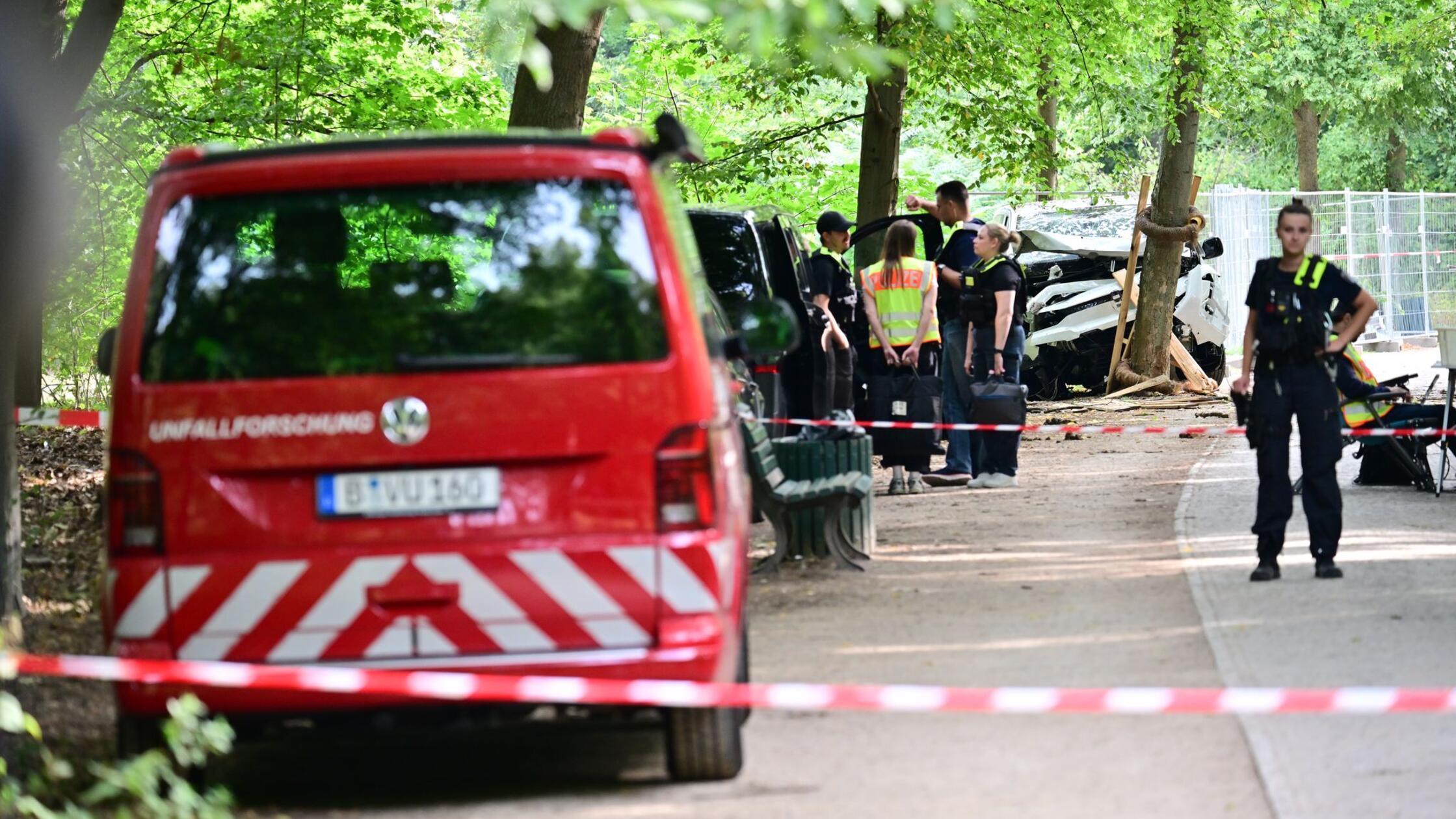 Polizisten stehen vor einem zerstörten weißen Fahr