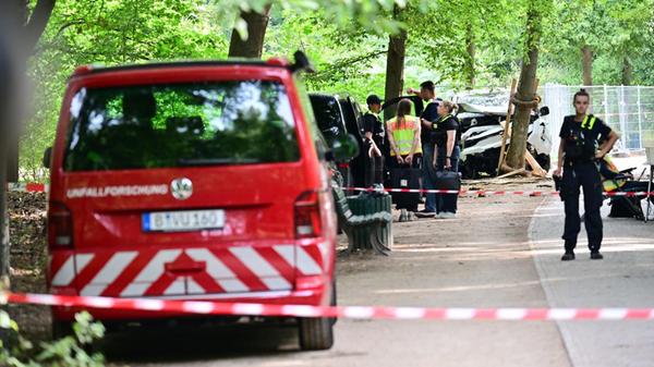 Polizisten stehen vor einem zerstörten weißen Fahr