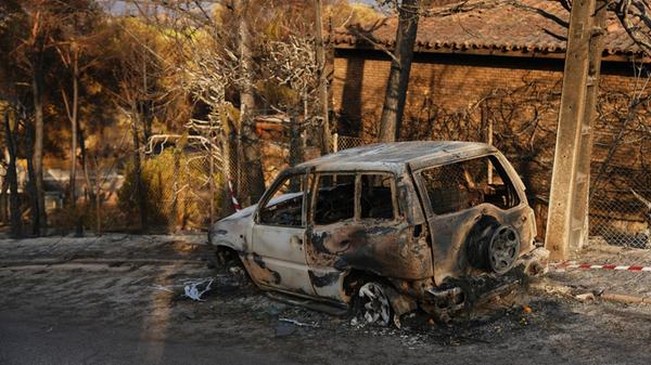 Ein durch einen Waldbrand zerstörtes Auto steht i