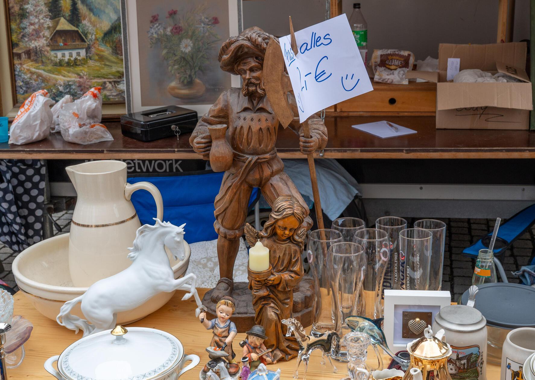 „Alles 2 Euro" stand auf dem handgeschriebenen Schild – geschnitzte Figuren und Gläser warteten auf neue Besitzer.