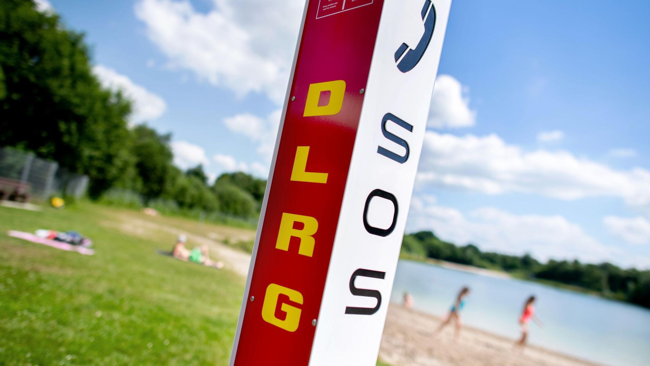 Eine Notrufsäule der DLRG steht an einem Badesee. 