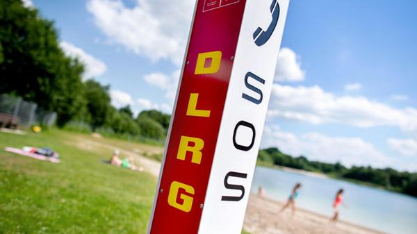 Eine Notrufsäule der DLRG steht an einem Badesee.