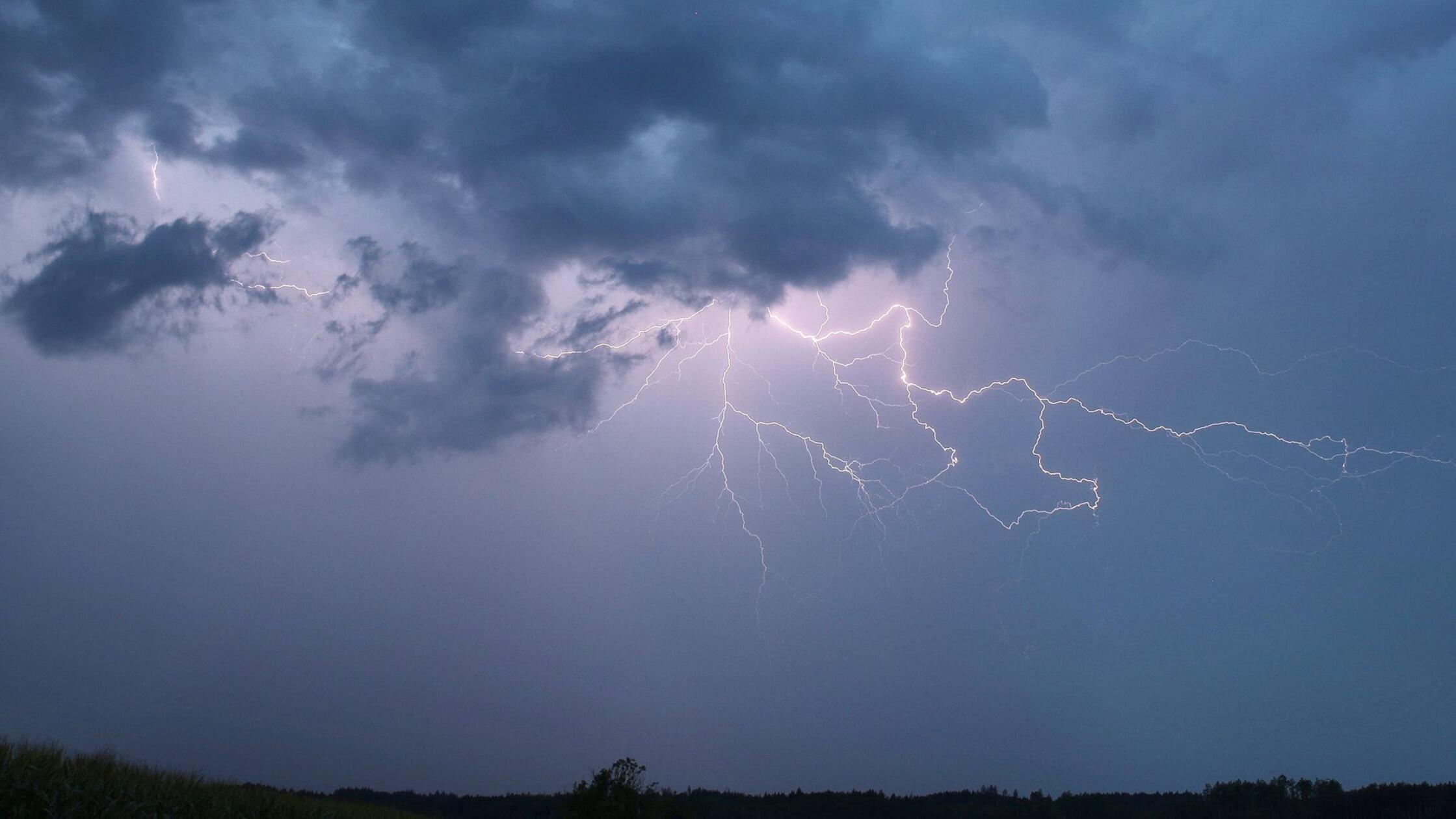 Ein Blitz zuckt bei einem Sommergewitter am abendl
