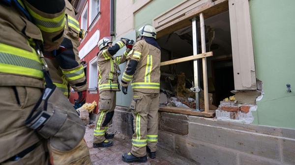 Einsatzkräfte der Feuerwehr sichern eine Hauswand,