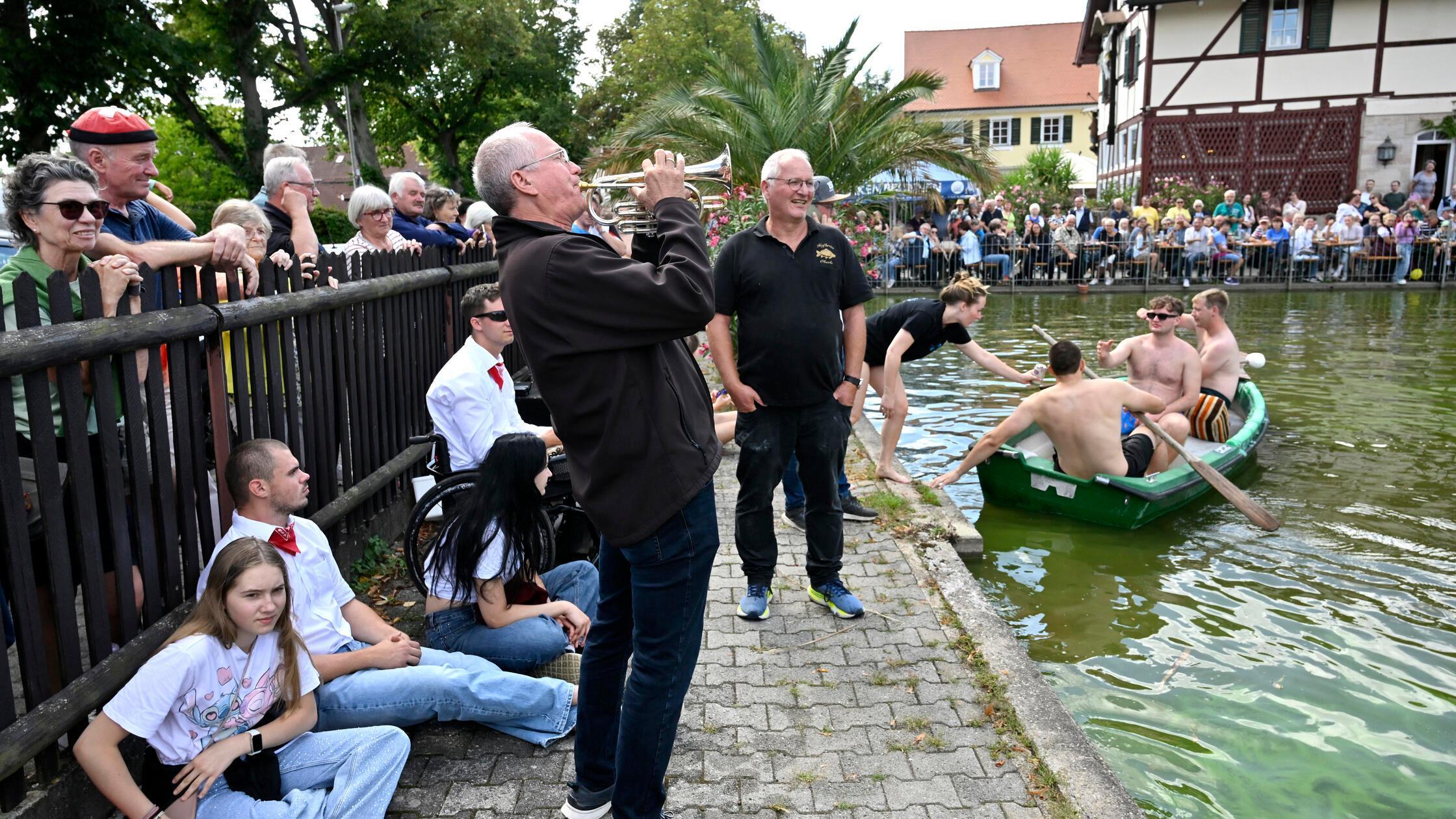 Traditionell findet während der Karpfen Kerwa im August in der Fischerei Oberle in Kosbach auf dem Hausweiher ein Fischerstechen statt, das immer viele Menschen anzieht. Im Bild: Martin Oberle gibt das trompetensignal für den beginn, dahinter sein Bruder Christoph Oberle, links Moderator David Carl