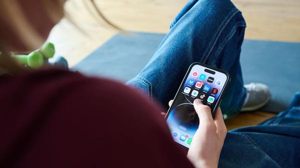 Ein Teenager sitzt am Boden und guckt auf ein Hand