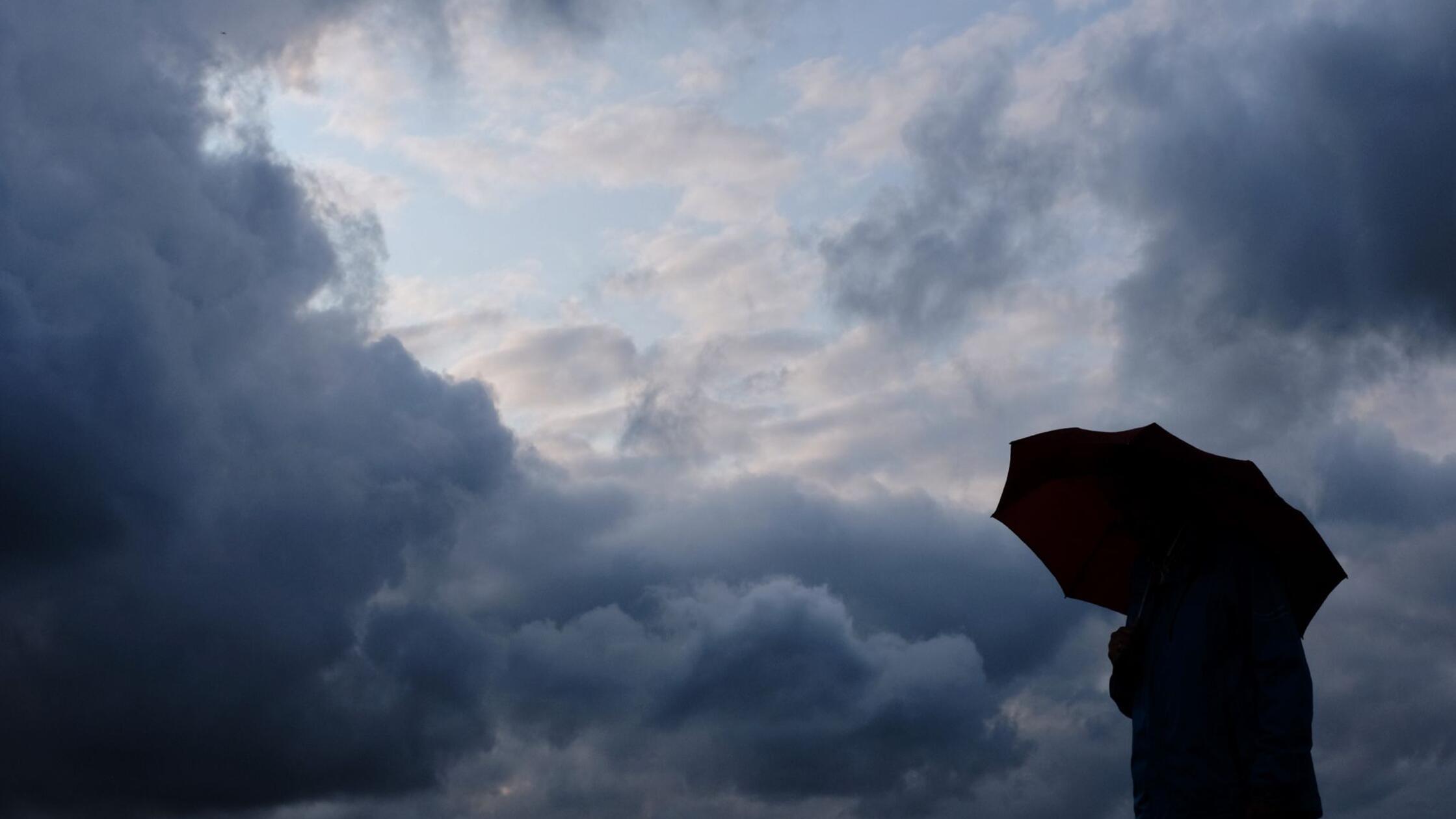 Ein Mann geht mit einem Regenschirm vor aufziehend
