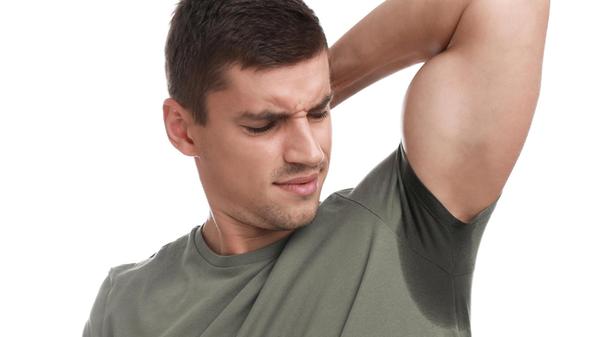 Young man with sweat stain on his clothes against