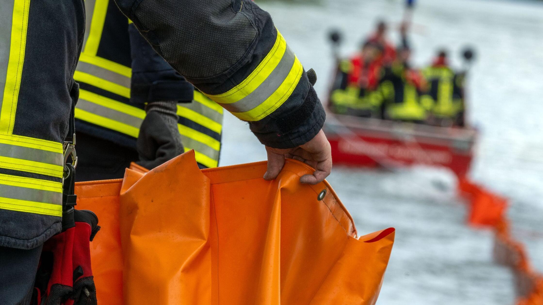 Eine Ölsperre wird aufs Wasser gezogen. Die Feuerw