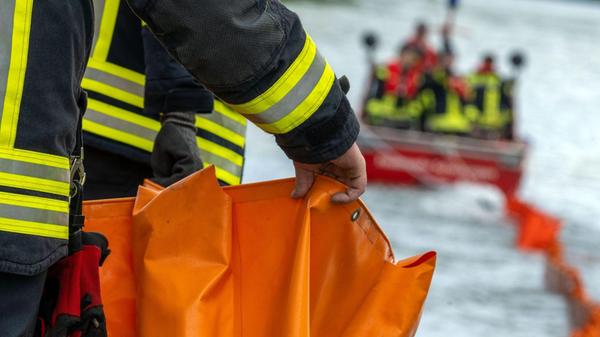 Eine Ölsperre wird aufs Wasser gezogen. Die Feuerw