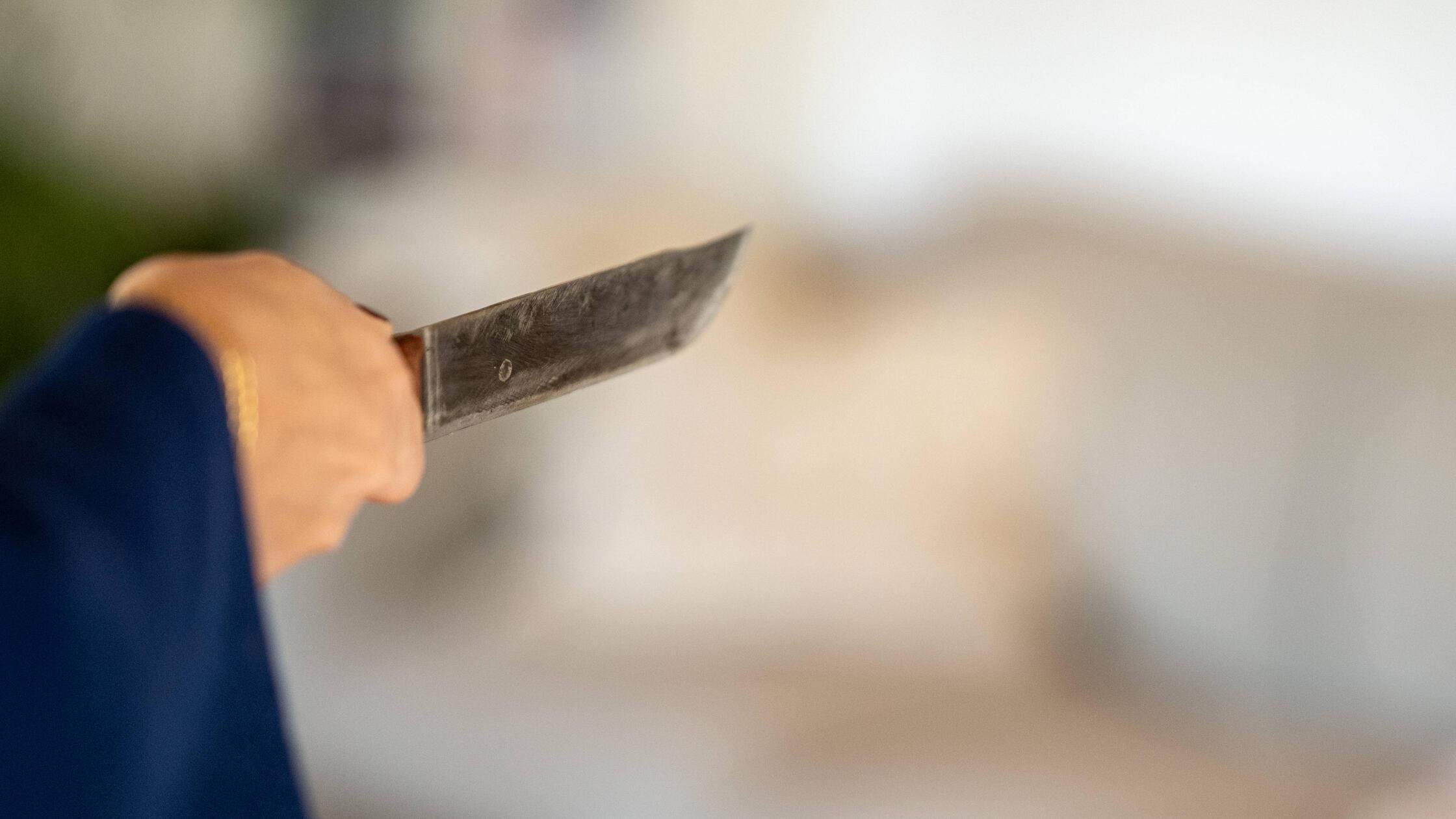 Frau mit Messer in Angriffspose.