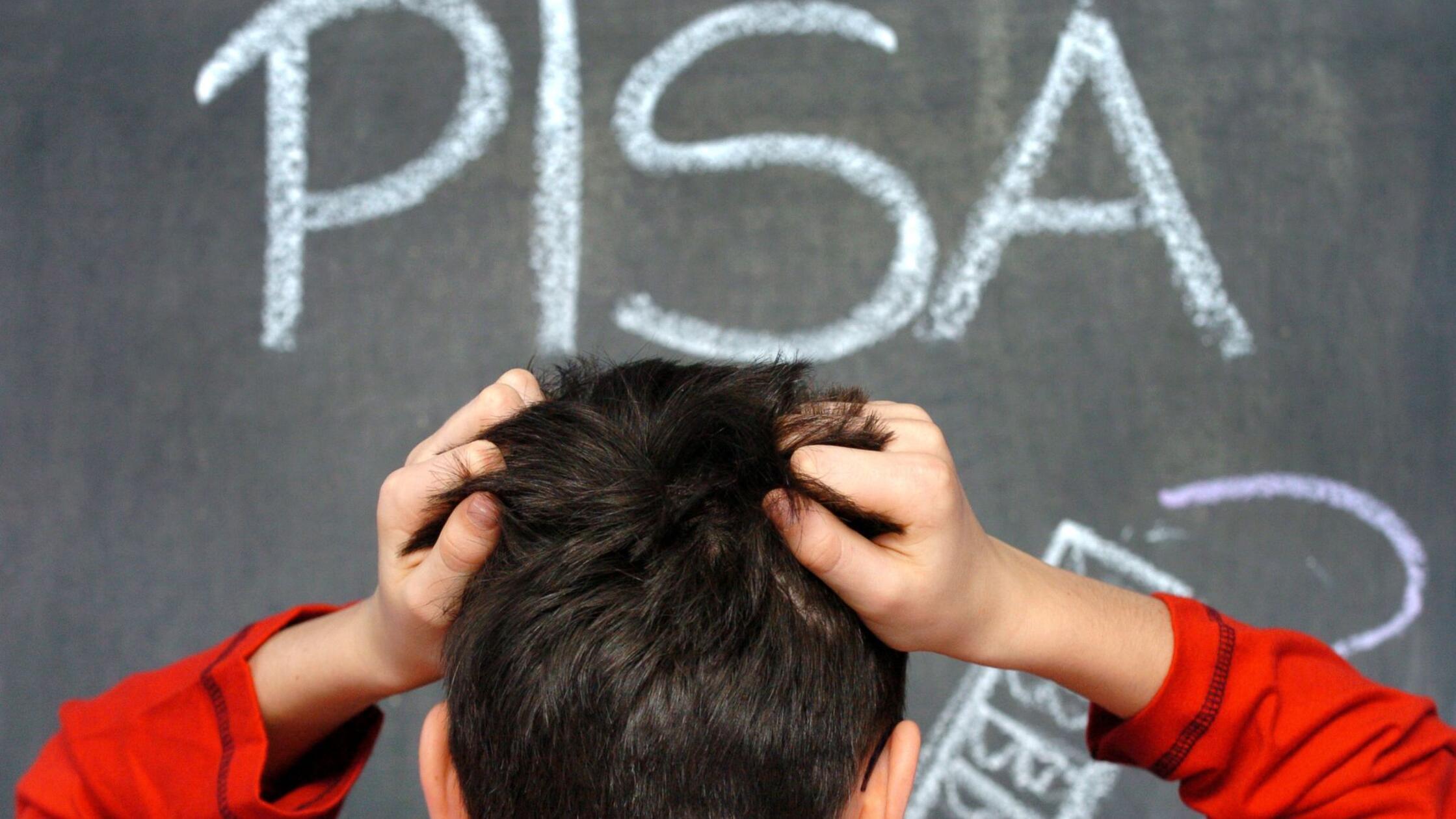 Ein Schüler rauft sich vor dem mit Kreide an eine 