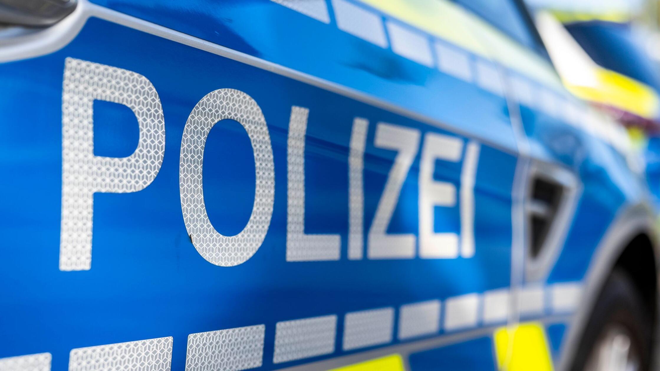 An der Tür von einem Streifenwagen steht der Schri