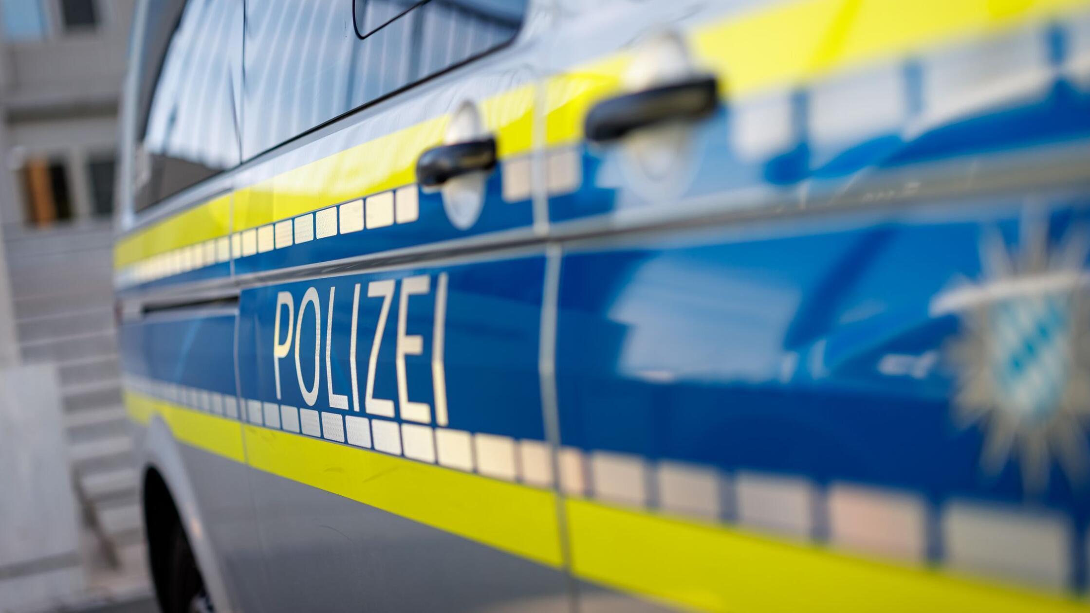 Polizei-Fahrzeug steht vor Gebäude (zu dpa: «Zwei 
