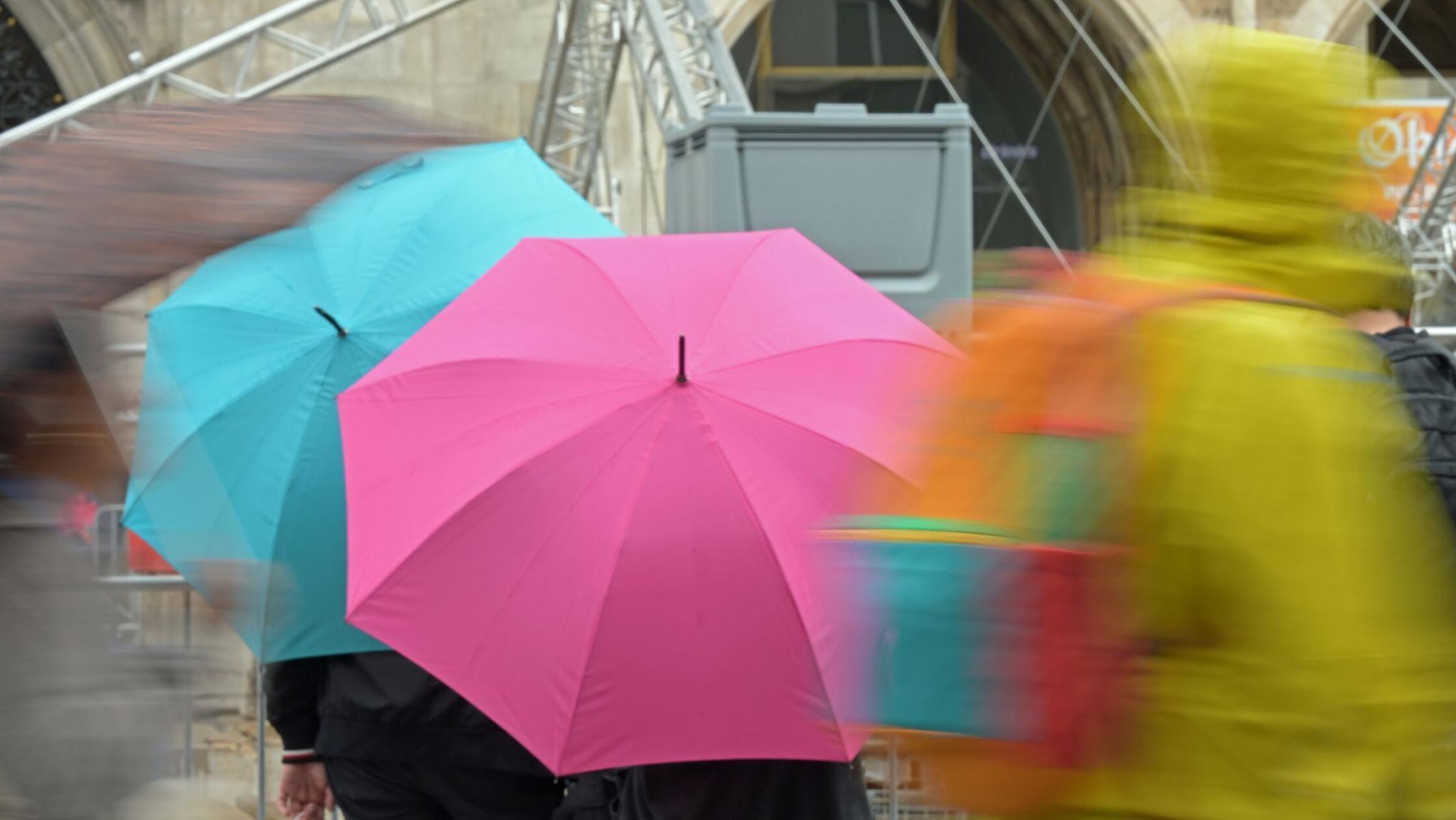 Passanten gehen mit Regenschirmen durch die Altsta