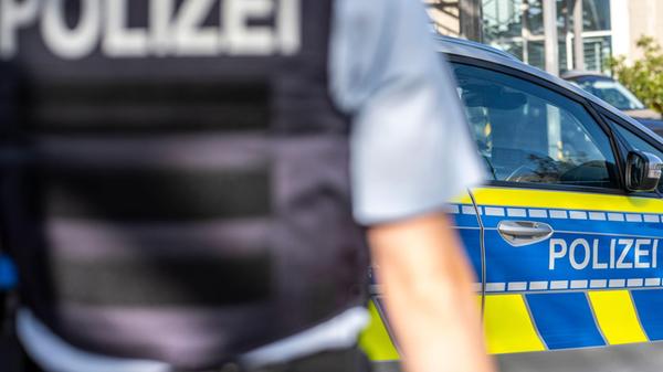 Ein Polizist steht vor einem Streifenwagen. Ermitt