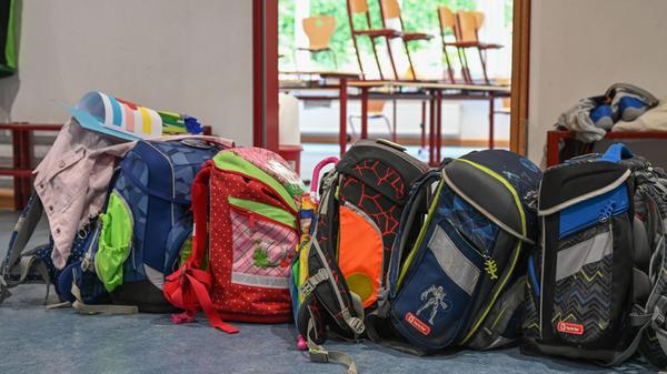 Schulranzen stehen vor einem Klassenzimmer. (zu dp