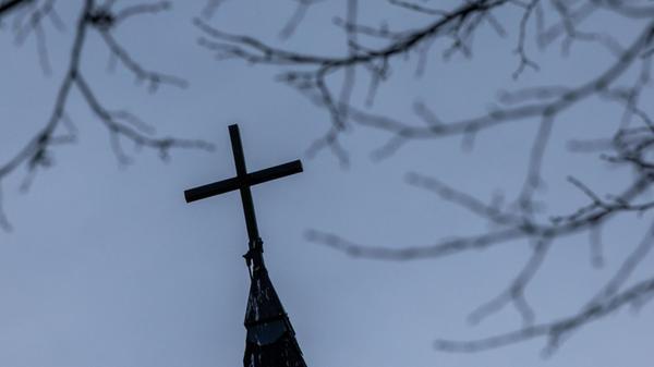 Ein Kirchenkreuz auf dem Dach der entwidmeten ehem