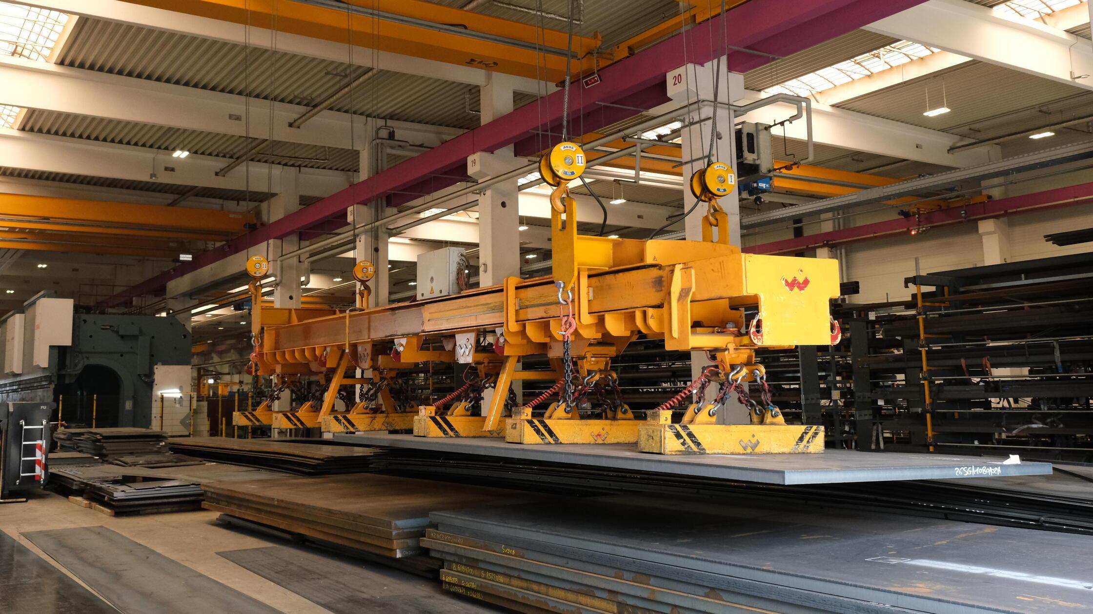 Am Anfang stehen große Metallplatten in unterschiedlicher Stärke und Länge. Mittels massiver Magnete und Deckenlaufkräne werden sie zu den unterschiedlichen Verarbeitungsstationen transportiert.