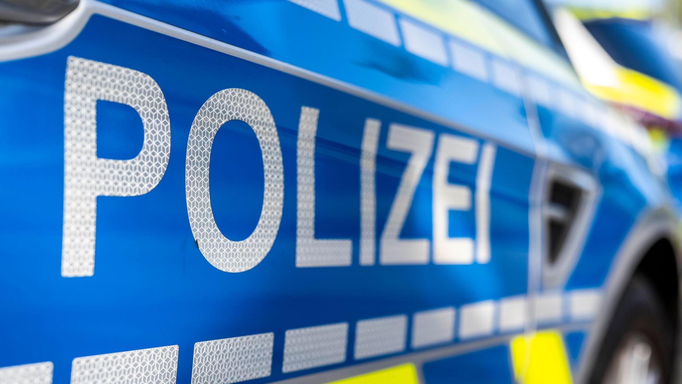 An der Tür von einem Streifenwagen steht der Schri