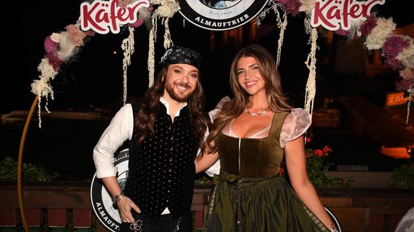 Der Moderator Riccardo Simonetti und Farina Opoku zeigen sich beim Almauftrieb im Käferzelt in München.